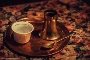 Bosnian coffee in a copper džezva on a tray beside a small white fildžan cup