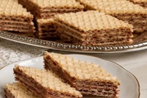 Rectangular wafer cake pieces with thin chocolate-nut filling layers on a white plate and serving tray.